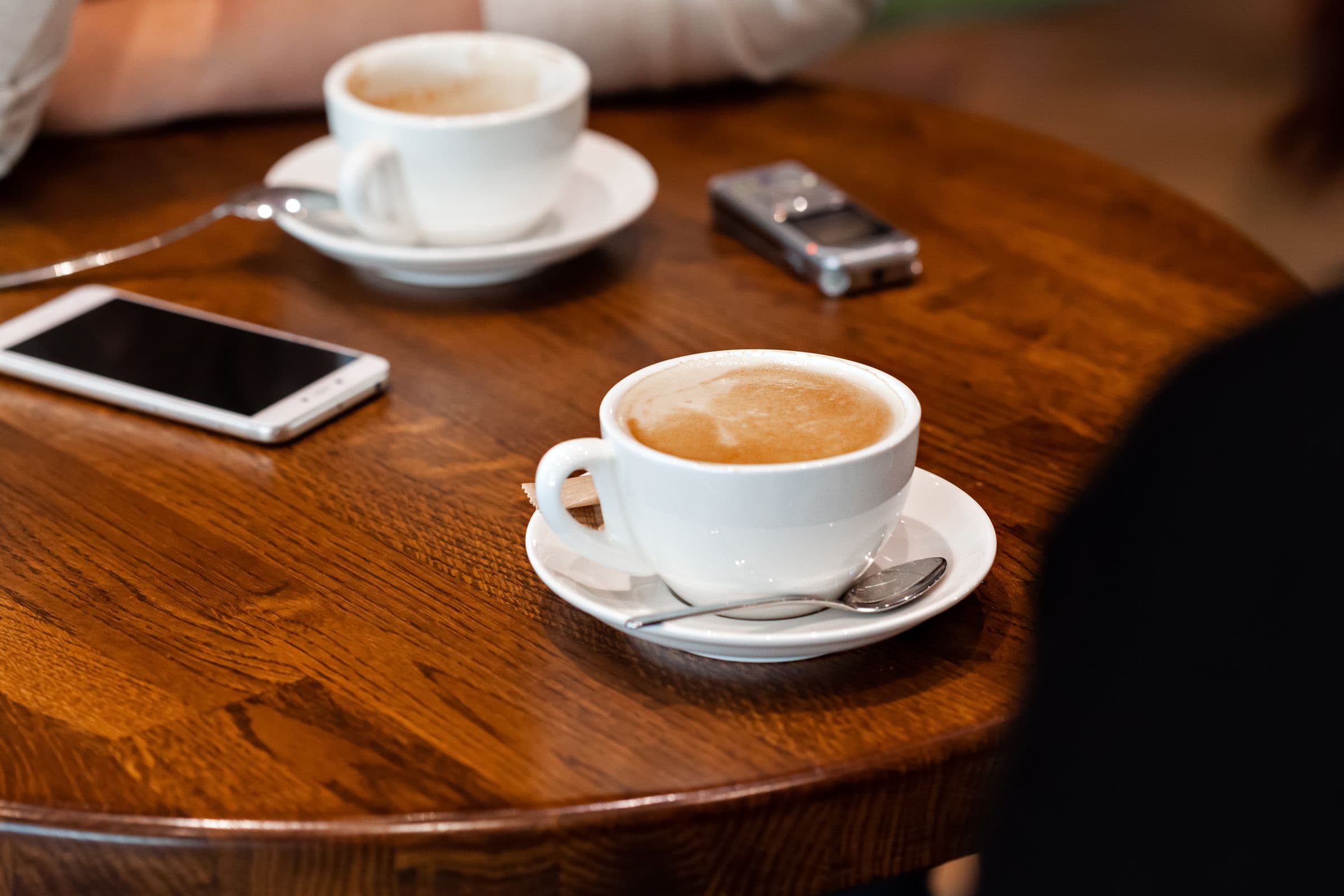 Två kaffekoppar och en telefon på ett bord efter ett möte